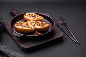 Delicious baked pear with dorblu cheese, walnut and honey on a textured concrete background