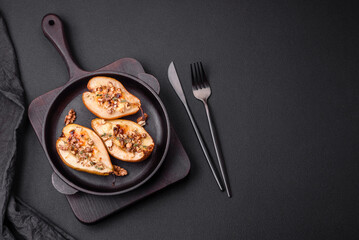 Delicious baked pear with dorblu cheese, walnut and honey on a textured concrete background