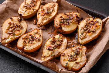 Delicious baked pear with dorblu cheese, walnut and honey on a textured concrete background