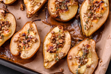 Delicious baked pear with dorblu cheese, walnut and honey on a textured concrete background