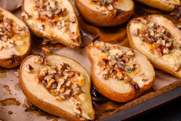 Delicious baked pear with dorblu cheese, walnut and honey on a textured concrete background
