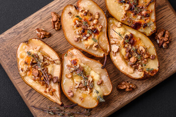 Delicious baked pear with dorblu cheese, walnut and honey on a textured concrete background