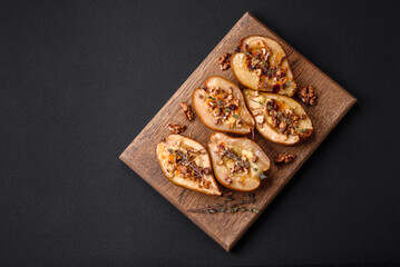 Delicious baked pear with dorblu cheese, walnut and honey on a textured concrete background