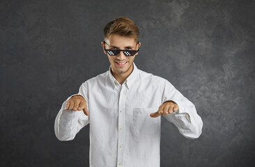Confident young man in thug life glasses smiling, dancing, enjoying music and having fun. Happy guy...