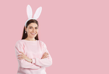 Happy Easter bunny girl on pink copy space background. Beautiful young woman wearing pastel pink...