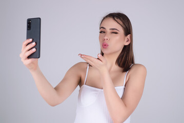 Young woman with phone, isolated on studio background. Business woman using smartphone. Business talk. Girl using cellphone, chatting online. Young woman using mobile phone.