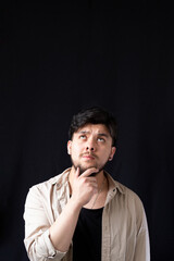 Light-eyed white young man touching his chin while looking up into an empty space