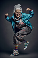 Elderly but agile smiling womman dressed in Hip - Hop style dancing breakdance - AI generative