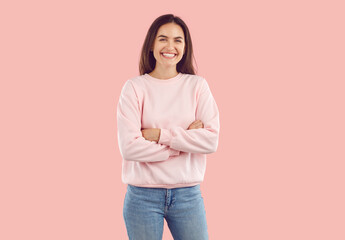 Portrait of happy woman standing with her arms folded. Laughing attractive brunette girl in pink...