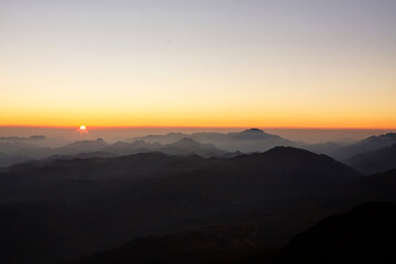 Beautiful sunrise view of Sinai mountains with the peaks in fog clouds.
