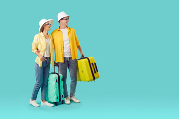 Cheerful young Caucasian man and woman with big tourist suitcases smiling looking at copy space...