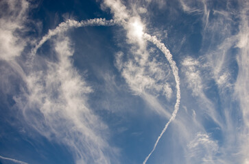 Niebo z chmurami biała smuga kondensacyjna po przelatującym samolocie.