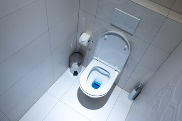 View of the white toilet bowl in the toilet. Bathroom finished with white glaze tiles and white...