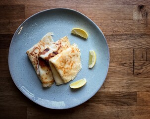 Pancake crepe on a blue plate, wooden table top view