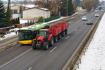 A bus, tractor, trucks and cars are traveling along the way.