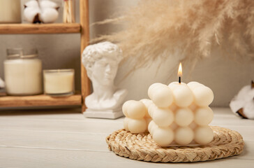 Soy wax candle on a textured table. Interior decor with a handmade burning candle. Hygge home...
