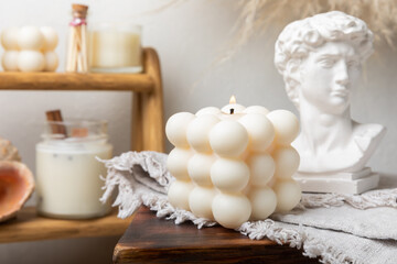 Soy wax candle on a textured table. Interior decor with a handmade burning candle. Hygge home...