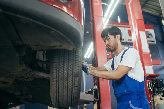 Automotive Asian mechanic worker checking at car tyre rubber condition needed for replacement. after service at auto repair shop concept