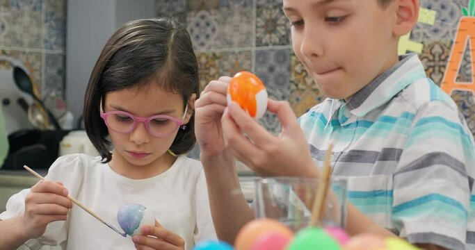 Cute kids painting eggs in a room decorated for easter day. Preparation for easter day