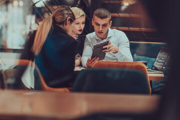 Photo through the glass of a group of business people sitting in a cafe and discussing business plans and ideas for new online commercial services