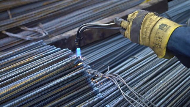 professional worker processes metal rods with a flame of a welding machine in the territory of the metal base