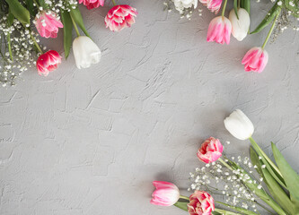 Pink tulips and white gypsophila flowers bouquet on a stylish gray stone background. Mothers Day, birthday celebration concept. Copy space for text
