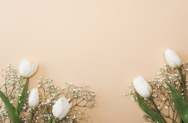 White tulips and gypsophila flowers bouquet on a beige background. Mothers Day, birthday celebration concept. Copy space for text. Mockup