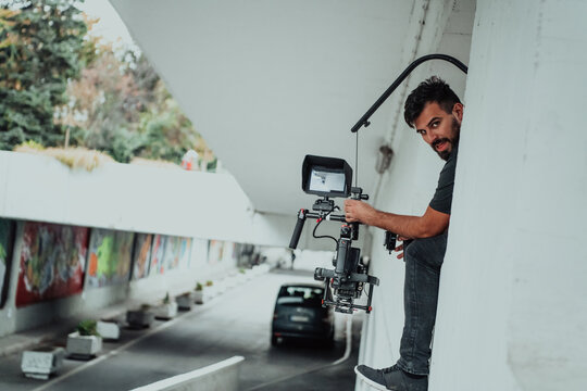 A professional cameraman with equipment and a stabilizer recoding two woman for a commercial advertisement as they run in an urban environment