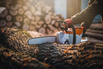 Cordless Chainsaw. Close-up of woodcutter sawing chain saw in motion, sawdust fly to sides....
