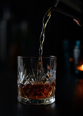 Pouring a glass of whiskey with a cocktail measurer in a fancy bar