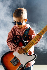 Dziecko gra na gitarze elektrycznej - rockowy chłopiec w studiu - zespół muzyczny - mały muzyk - obrazy, fototapety, plakaty