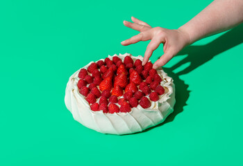 Pavlova cake with fresh berries isolated on a green background. Homemade meringue cake, an australian recipe