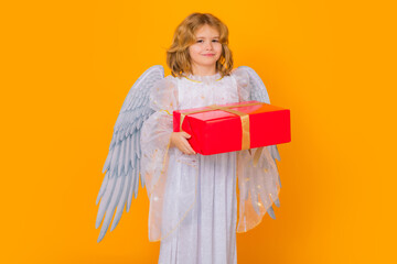 Angel with gift box present. Valentines day. Kid with angel wings. Studio portrait of angel child...