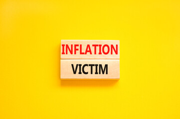 Inflation victim symbol. Concept words Inflation victim on wooden block. Beautiful yellow table yellow background. Business inflation victim concept. Copy space.