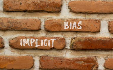 Implicit bias symbol. Concept words Implicit bias on red brown brick wall. Beautiful red brown brick wall background. Business psychology implicit bias concept. Copy space.