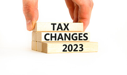 Tax changes 2023 symbol. Concept words Tax changes 2023 on wooden blocks on a beautiful white table white background. Businessman hand. Business Tax changes 2023 concept. Copy space.