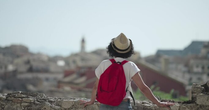 Tourist travel woman in Corfu, Greece. Happy elegant fashion model enjoying vacation in old town visiting famoust landmarks in Crofu island, Greece, slow motion