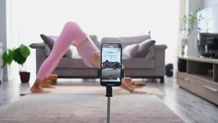 woman practicing yoga poses stretching in front of phone camera sport blogger teacher yoga online class wellness coach