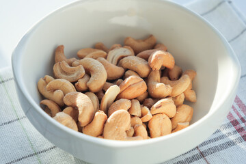 cashew nuts in a white color bowl on table 