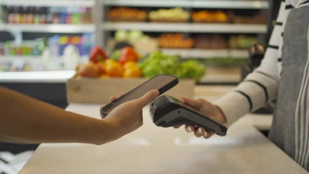 People shopping in a supermarket or retail shop, buying snacks and food by online credit card on mobile phone in cashier on grocery products shelves. Food shopping. People lifestyle.  Checkout service