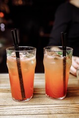 Refreshing grapefruit cocktail with ice and rosemary on a grey background.