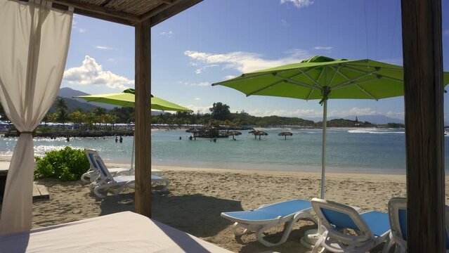 Beach cabanas overlooking the Caribbean Sea. Relax in the shade. Beach, sand, umbrellas, loungers, curtains, palm trees, beach beds. Adrenaline Beach, Labadee, Haiti private resort by Royal Caribbean.