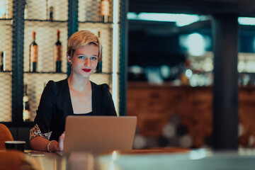 Businesswoman sitting in a cafe while focused on working on a laptop and participating in an online meetings. Selective focus.