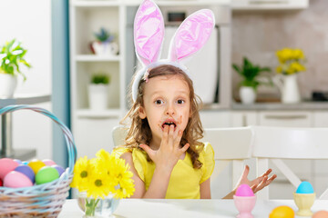 A child in bright clothes eating Easter chokolate eggs