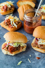 Homemade pulled pork sliders buns with tangy barbecue sauce, ready for eating.