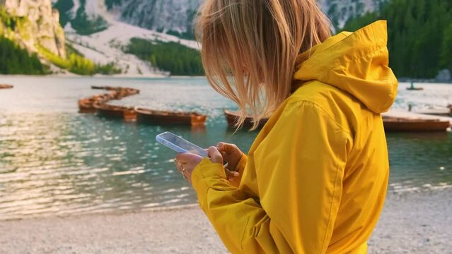 Woman uses smartphone and posting photos of Lake Braies in social media. 