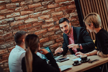 Happy businesspeople smiling cheerfully during a meeting in a coffee shop. Group of successful business professionals working as a team in a multicultural workplace.