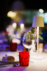 a table with a white tablecloth, glasses, crockery and decor in dark restaurant