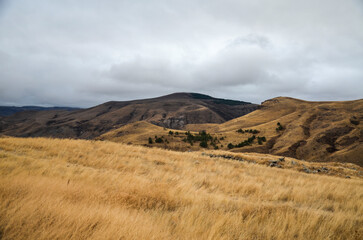 Picturesque atmospheric armenian autumn mountain landscape with gentle slopes of mountainous terrain and meadows with yellow dry grass of the South Caucasus