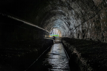 Underground vaulted urban sewer tunnel with dirty sewage - obrazy, fototapety, plakaty